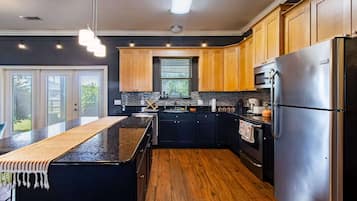 Una cocina moderna con una isla central, armarios negros, electrodomésticos de acero inoxidable y suelo de madera.