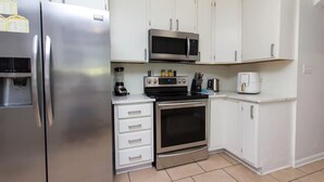 A modern kitchen with stainless steel appliances, white cabinetry, and a tiled floor. - Navarre Oasis: Tiki Bar, Hot Tub, Near Beach (Navarre)