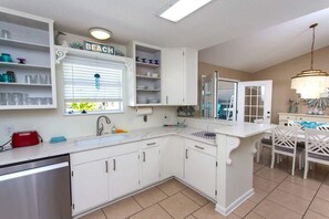 A kitchen with white cabinetry, a built-in oven, a sink, and a window with blinds. - Navarre Beach Retreat | Hot Tub & Teen Bunkhouse (Navarre)