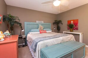 A bedroom with a bed, bedside table, lamp, and a painting on the wall. - Navarre Beach Retreat | Hot Tub & Teen Bunkhouse (Navarre)
