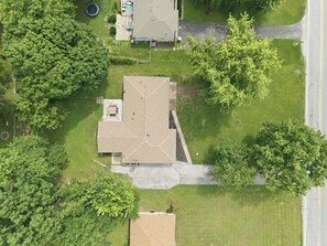 An aerial view of a residential area with a house, a driveway, and surrounding greenery. - Indy 3BR | Game Room + Fire Pit | Sleeps 8 (Indianapolis)