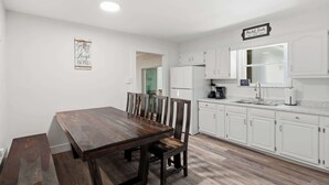 Eine moderne Küche mit weißen Schränken, einem Holztisch und einem Schild mit der Aufschrift 'Market Fresh'.