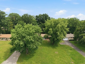 A residential area with multiple houses, a paved driveway, and a grassy lawn. - Firepit & Gameroom Retreat in Devon Hills (Indianapolis)