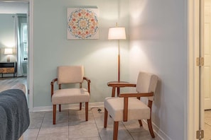 A room with two wooden chairs, a floor lamp, and a decorative wall piece.