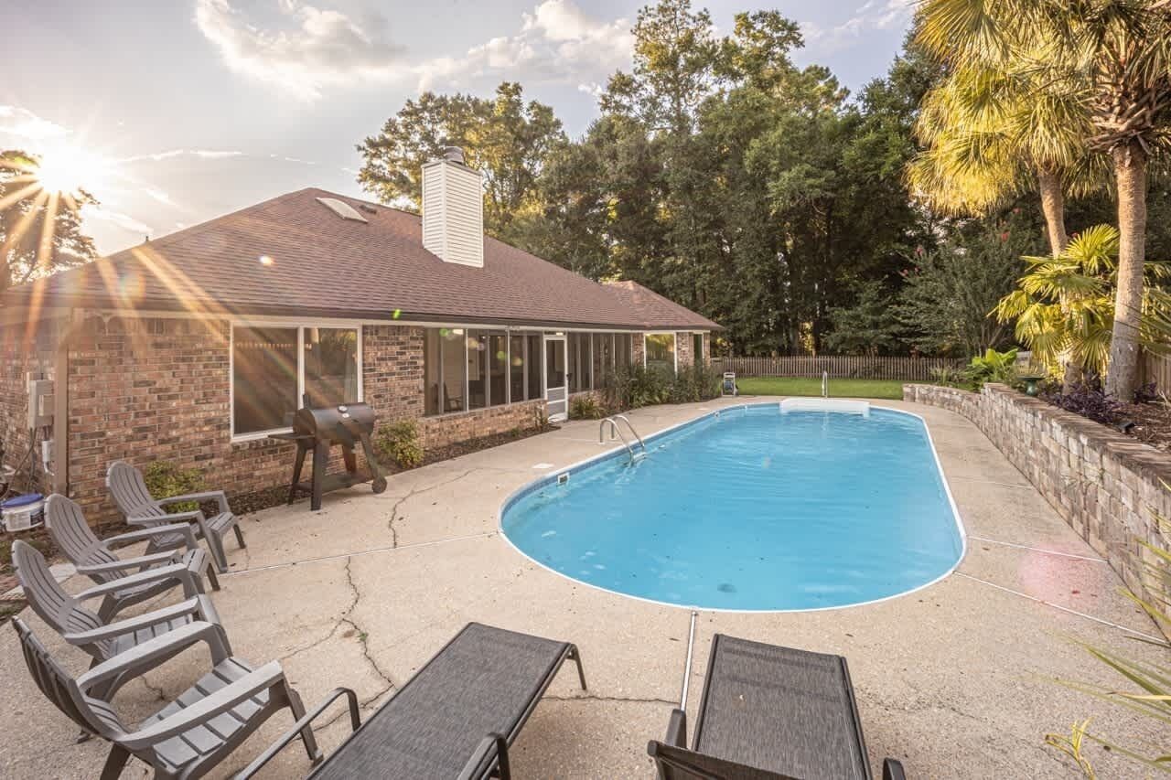 Ein Garten mit Swimmingpool, Terrassenmöbeln und einem Ziegelhaus.