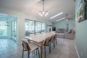 A spacious dining area with a large table and chairs, a ceiling fan, and a view through the glass doors. - Private Pool | 3BR/3BA | Near Pensacola Beach (Pensacola)