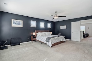 Une chambre à coucher avec un lit, un ventilateur de plafond et une porte donnant sur une autre pièce.