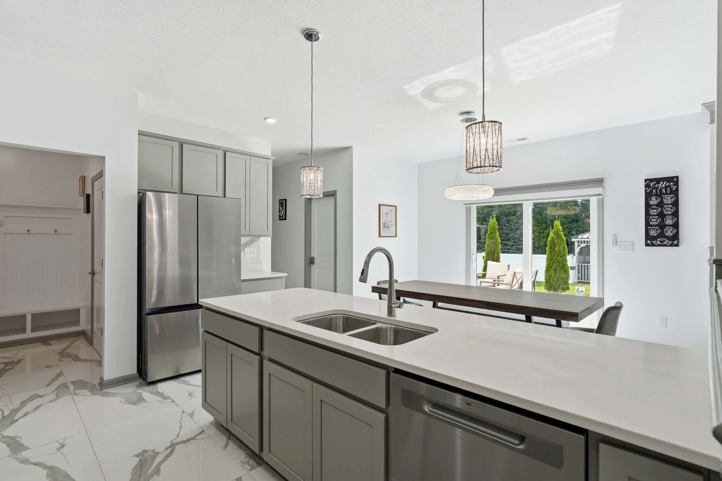 A modern kitchen with stainless steel appliances, a marble floor, and a view of the outdoors.