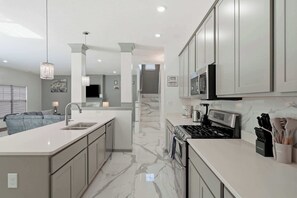 A modern kitchen with a central island, stainless steel appliances, and a grey color scheme.
