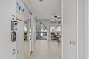 A hallway leading to a balcony with a ceiling fan, a sliding glass door, and a view of the outside. - Sandpiper Cove Unit 8248 Pet-Friendly | 3-minute walk to the beach (Destin)