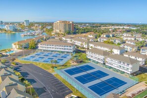 Ein Küstenhotel mit mehrstöckigen Gebäuden, einem Tennisplatz und einem Yachthafen.