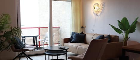 Ein Wohnzimmer mit einer Couch, Sesseln, einem Couchtisch und einer Topfpflanze.
