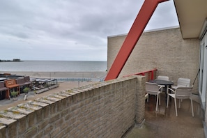 A balcony with a view of the beach and the sea, a brick wall, and outdoor seating. - Waterfront Apartment With Balcony (Makkum)