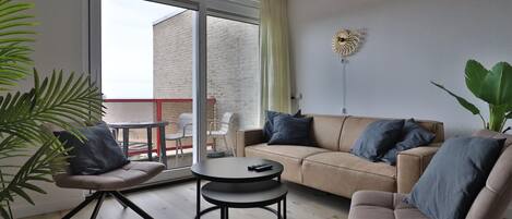 A modern living room with a sofa, two armchairs, a coffee table, and a large window with a view of a building.