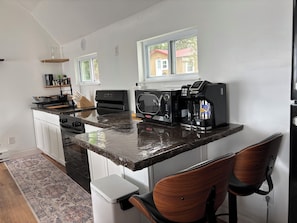 A kitchen with a built-in microwave, coffee maker, and a wooden chair.