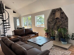 A modern living room with a brown leather sofa, a wooden coffee table, and a stone fireplace.
