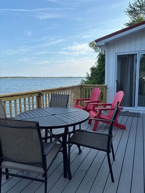 A deck with a table and chairs, overlooking a body of water.