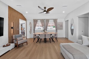 A modern living room with a dining area, a ceiling fan, and a view of the outdoors. - Coastal - 3BR King Suite - 15 Min to Anna Maria Island & IMG (Bradenton)