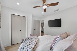 A bedroom with a bed, a ceiling fan, a flat-screen TV, and a door. - Coastal - 3BR King Suite - 15 Min to Anna Maria Island & IMG (Bradenton)