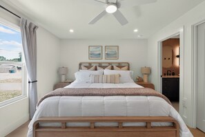 Ein Schlafzimmer mit Bett, Nachttischen, Deckenventilator und Kunstwerken an der Wand.