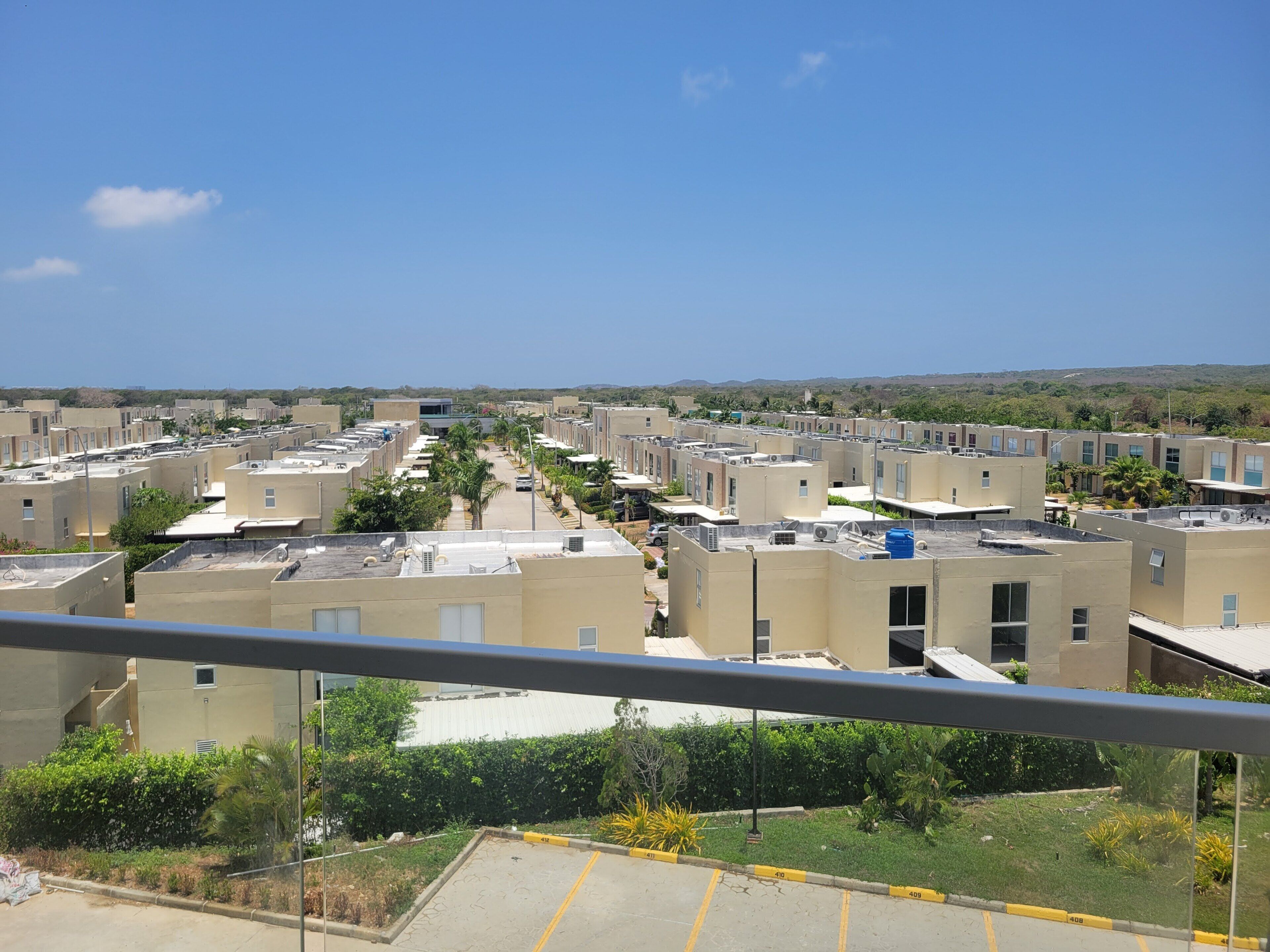 A residential area with multiple apartment buildings, a clear sky, and a parking lot.
