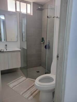 A modern bathroom with a glass-enclosed shower, a white toilet, and a sink with a mirror above it. - Cozy and intimate aparta-suite in the north Zone of Cartagena (Cartagena)