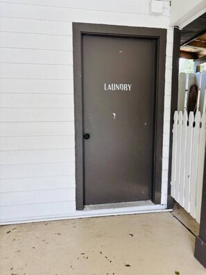 Eine Tür mit der Aufschrift 'LAUNDRY', im Hintergrund ein weißer Zaun.