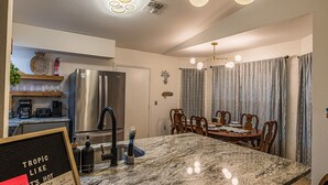 Una cucina moderna con un'isola grande, elettrodomestici in acciaio inossidabile e un'area pranzo con un lampadario.