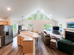 Eine geräumige Küche mit Kochinsel, eine Essecke mit Sofa, Fernseher und Kamin.