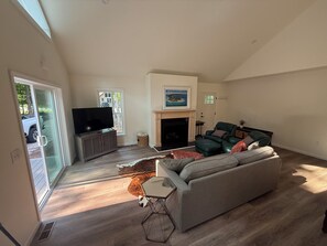 A spacious living room with a fireplace, a television, and a sofa. - Brand new, bright 4-bedroom house near ski hills! (Harbor Springs)