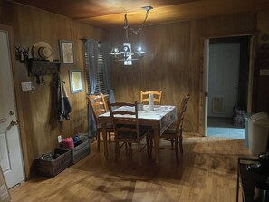 Ein Essbereich mit einem Holztisch und Stühlen, einer Chandelieber und einem fenster mit Vorhängen.