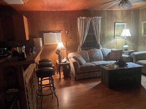 Ein gemütliches Wohnzimmer mit einer Couch, einem Couchtisch und einer Bar mit Hockern.
