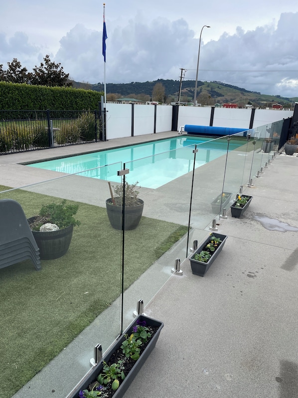 A swimming pool with a view of a body of water and hills in the distance.