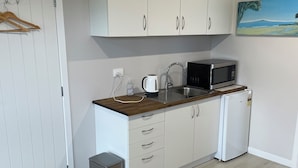 A compact kitchen with white cabinets, a microwave, a kettle, and a small trash bin. - Clean, warm and beautiful place to stay only 4 minutes to Cambridge. (Cambridge)