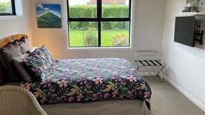 A bedroom with a bed, a window with a view of a garden, a chair, and a small table. - Clean, warm and beautiful place to stay only 4 minutes to Cambridge. (Cambridge)