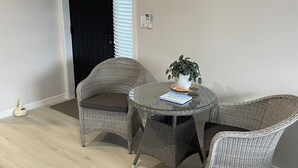 A room with a round glass table, wicker chairs, a potted plant, and an air conditioning unit mounted on the wall. - Clean, warm and beautiful place to stay only 4 minutes to Cambridge. (Cambridge)