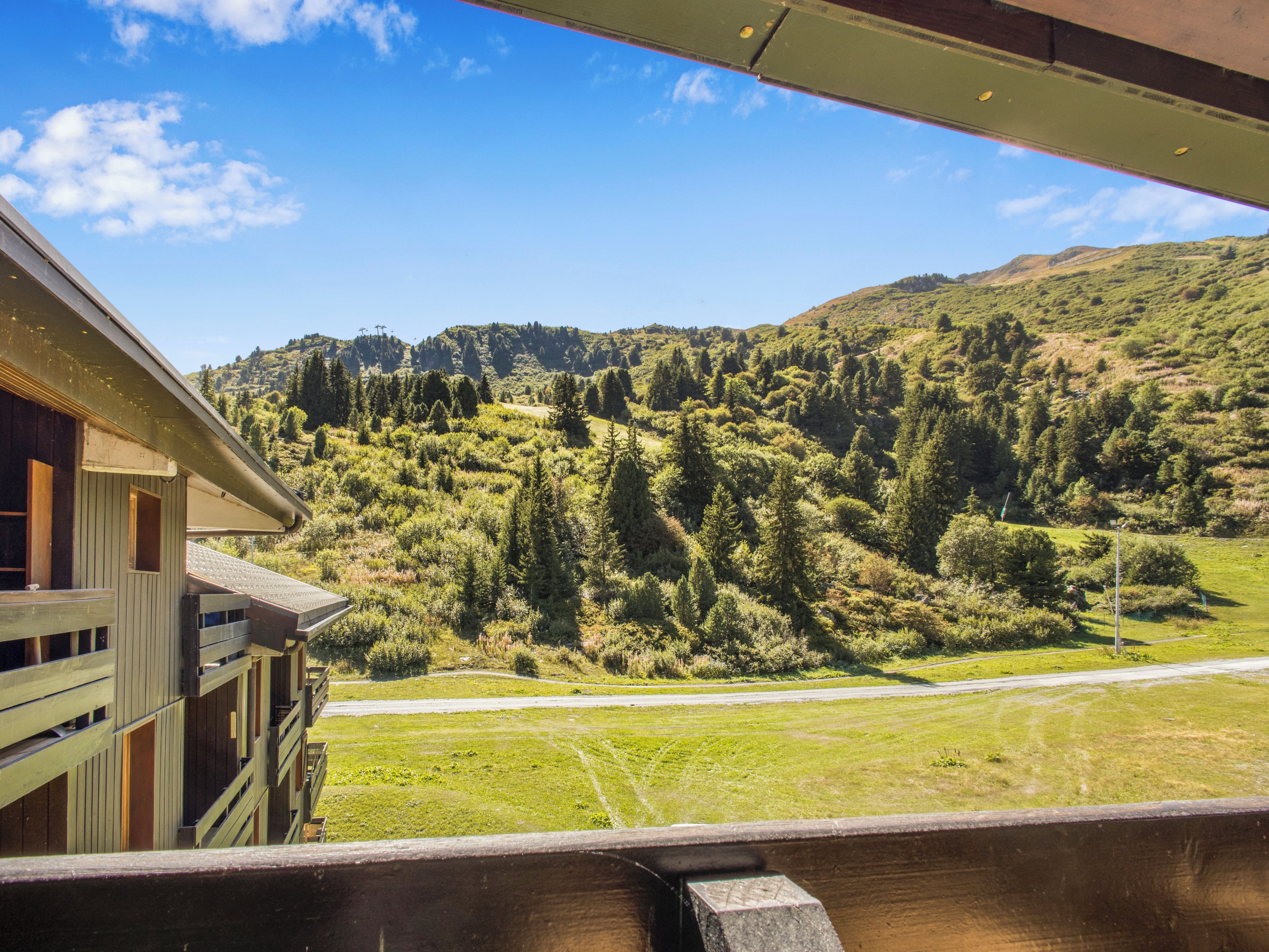 Une cabane en bois dotée d’un balcon donnant sur un paysage montagneux.