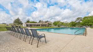 A swimming pool with a tiled deck and chairs, surrounded by a fence and trees. - Premium Cabin - Family Cabin Rental Sleeps 8-10 (Willis)