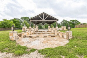 Ein steinernes Pavillon mit Dach, umgeben von einem gepflasterten Weg.