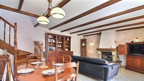 Comedor con mesa de madera para cuatro personas, sofá y chimenea.