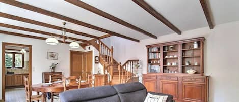 A spacious living area with a staircase, wooden furniture, and a bookshelf.