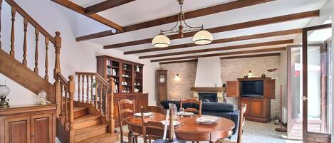 A wooden staircase leading to a dining area with a table set for two, a fireplace, and a television in the background.
