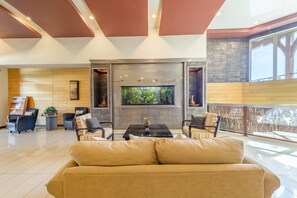 Eine geräumige Lobby mit einer großen Couch, einem Couchtisch und einem Fernsehbildschirm.