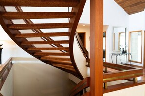 Eine Wendeltreppe mit Holzgeländern und einer Glasböden, die zu einer oberen Ebene führt.