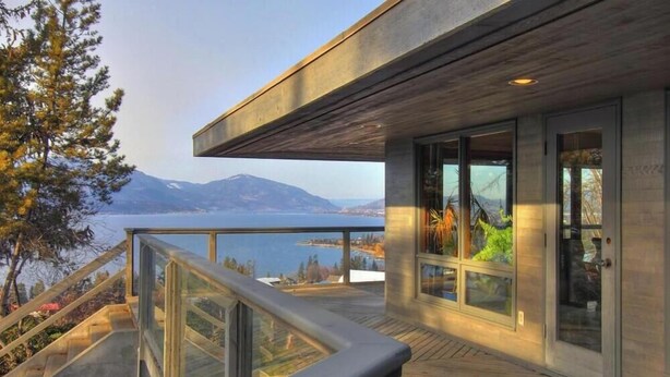 A modern building with a balcony overlooking a body of water and mountains. - Stunning Vineyard Estate House (Kelowna)