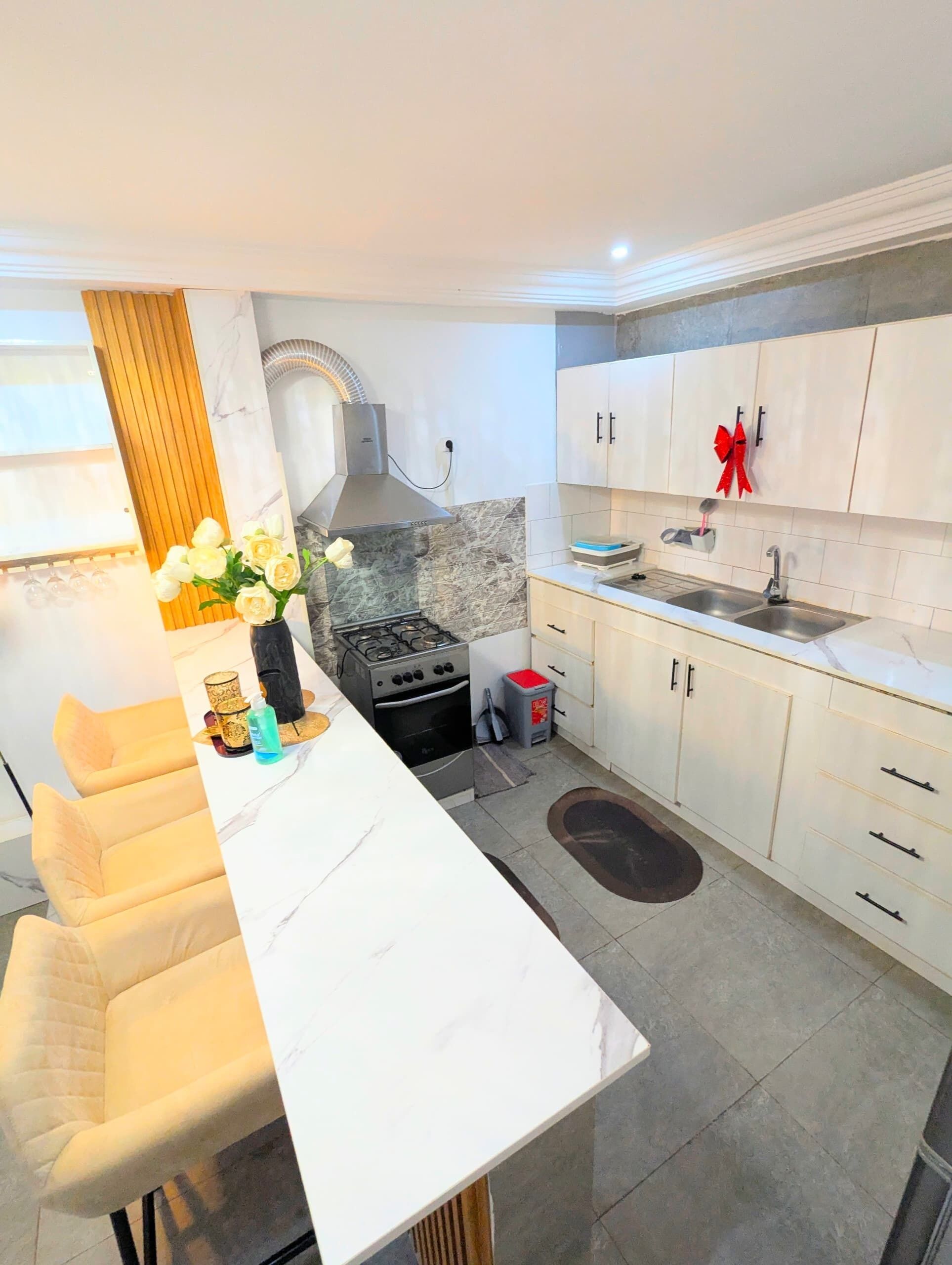 A modern kitchen with white cabinets, a gas stove, a range hood, and a dining area with a white table and chairs.