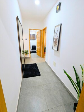 A hallway with a tiled floor, a black rug, a wooden door, and a framed picture on the wall. - STYLE AND COMFORT IN THE HEART OF THE CITY (LOME)
