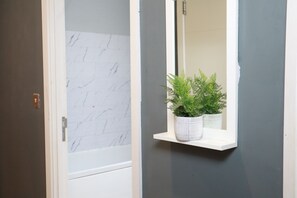 A bathroom with a white marble wall, a white door, and a white shelf with a potted plant. - Luxury Modern Flat BHX NEC JLR Solihull Hospital with Free Secured Parking (Solihull)