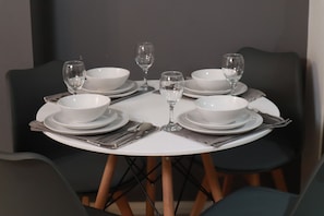 A round dining table set for six with white plates, bowls, and cutlery. - Luxury Modern Flat BHX NEC JLR Solihull Hospital with Free Secured Parking (Solihull)