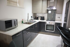 A modern kitchen with a microwave, sink, coffee maker, and stove. - Luxury Modern Flat BHX NEC JLR Solihull Hospital with Free Secured Parking (Solihull)